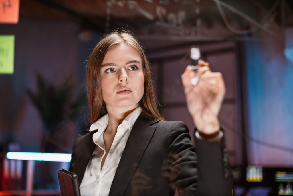 Young Focused Woman Writing On Glass Office Board In Modern Office - Contabilidade em Joinville - SC | Dunzer - Contabilidade consultiva: saiba como ela pode ajudar novos empresários